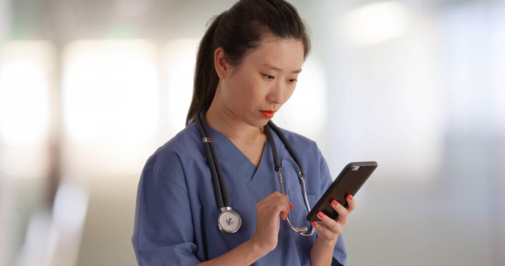 Doctor looking at smartphone in hospital