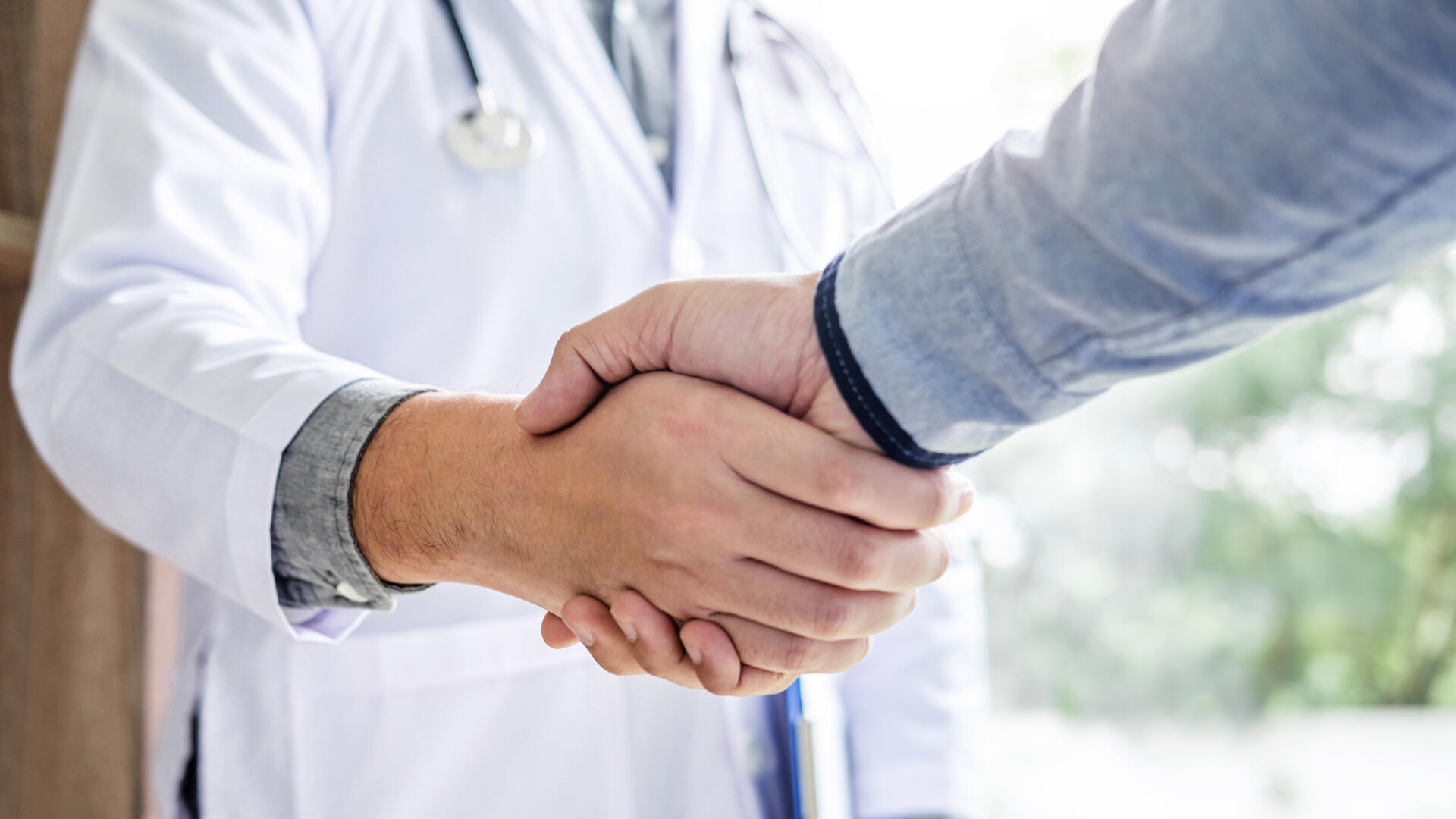Doctor in white coat handshake with patient