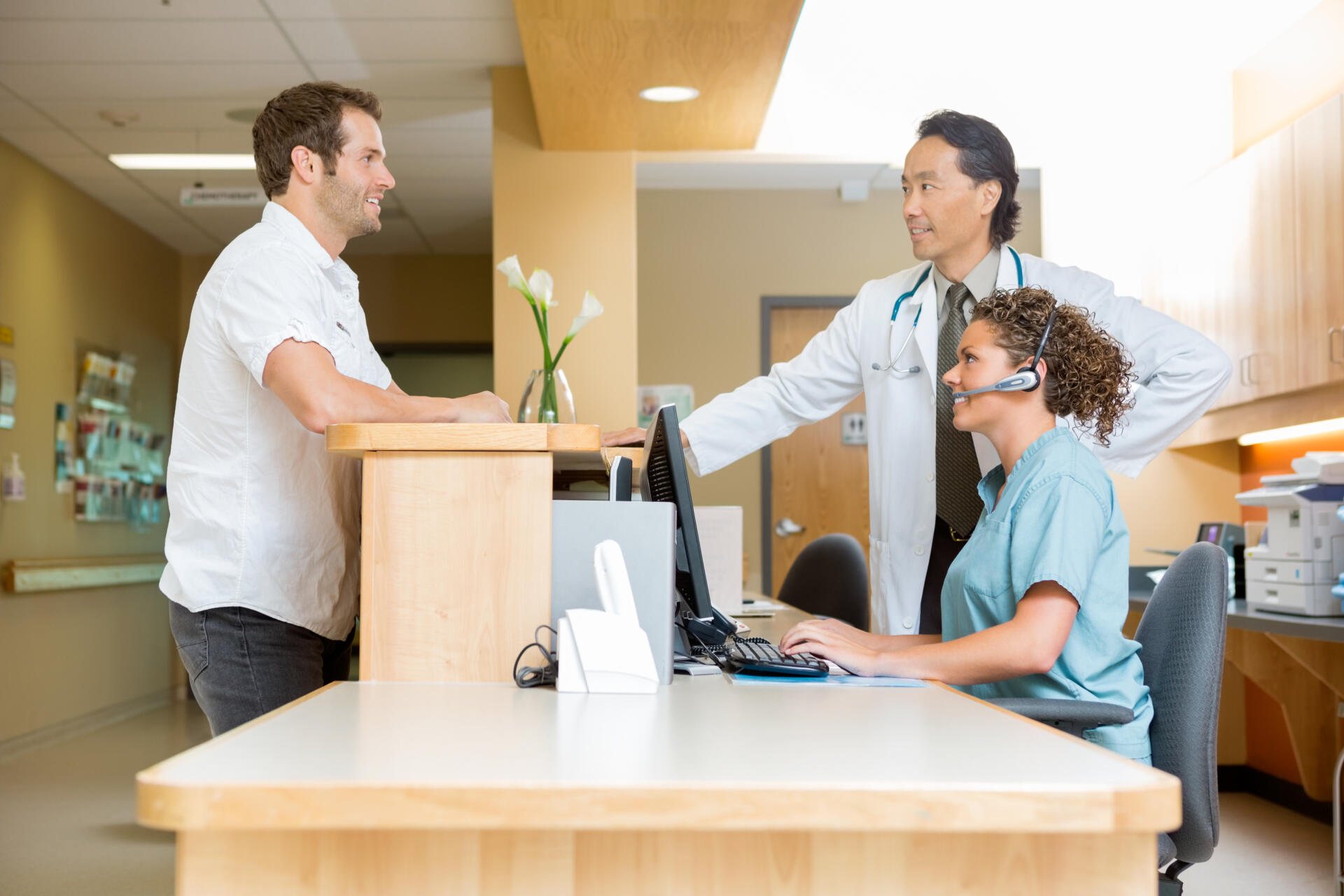 Patient With Doctor And Nurse At Reception Desk