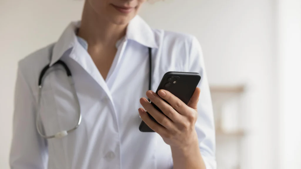 Close up focus on smartphone in young doctor hands.