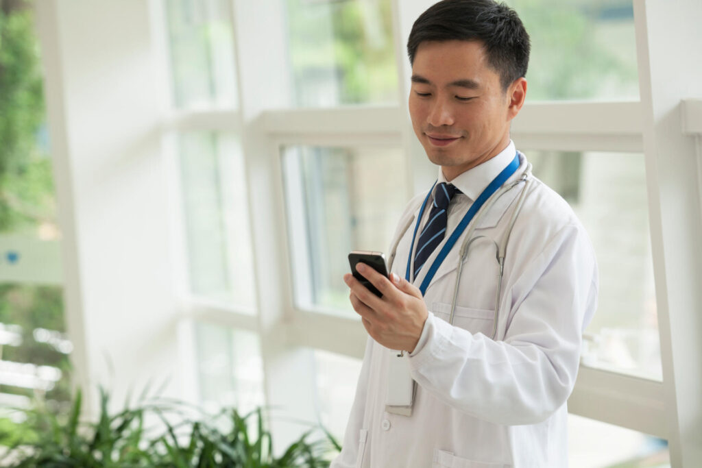 Smiling doctor looking down at his phone