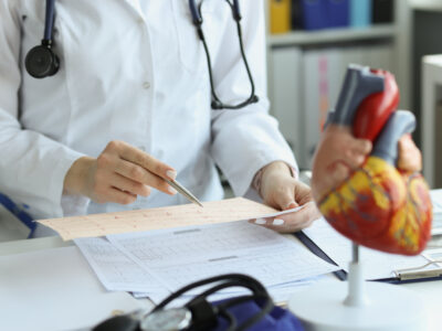 Cardiologist doctor holding and reading an ecg paper report of patient with heart disease. Cardiovascular disease and treatment concept